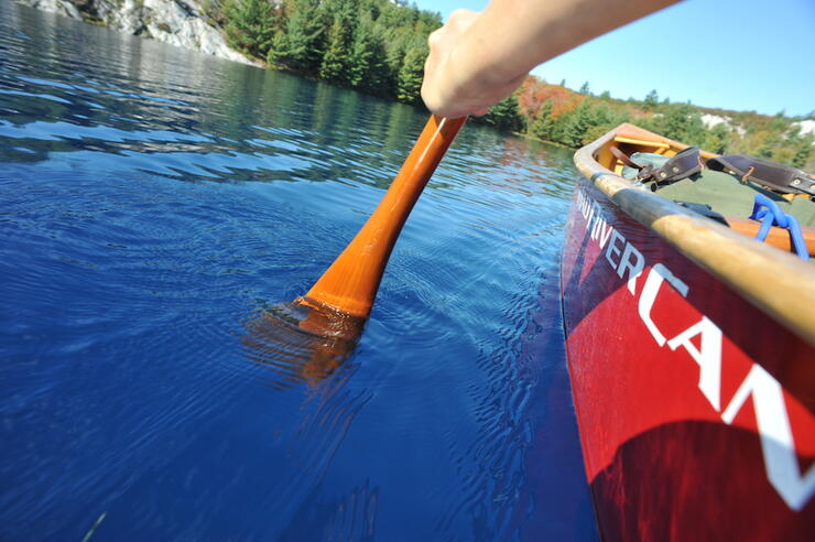 Canoeing photo shot low by the water of a blue-water lake in Ontario