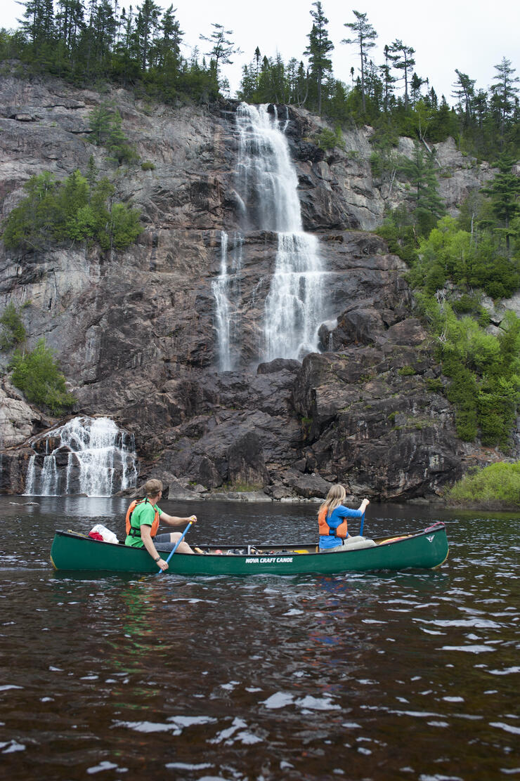 People canoeing beside a waterfall