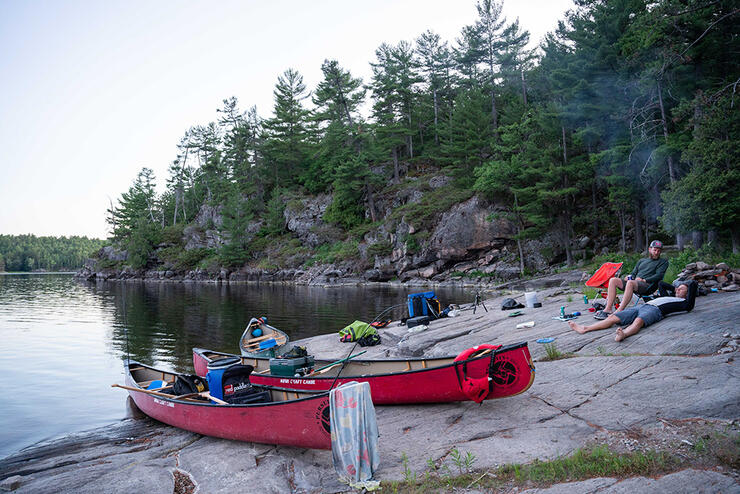 Red canoes and camping gear on shore.