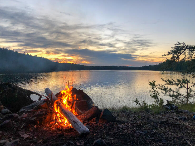 Campfire burns at dusk on the shore of Lake Temagami