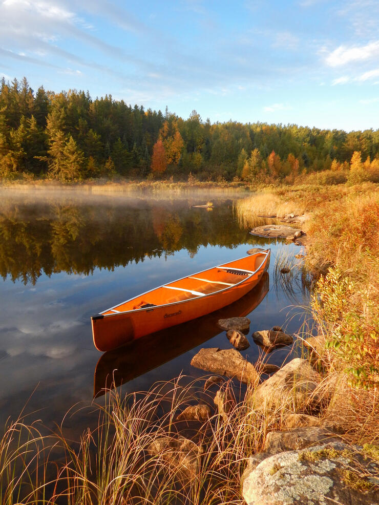 Empty canoe waits near shore with mist on water