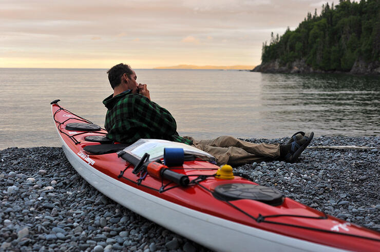 Man leaning on a kayak enjoying the peaceful backcountry