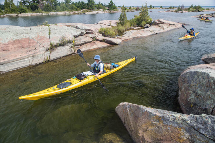 Yellow sea kayaks paddling between rocky channels.