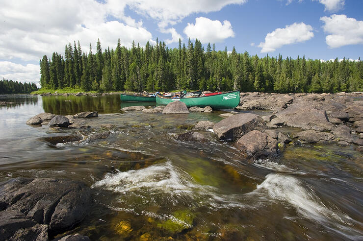 Green Canoes by rocky shore