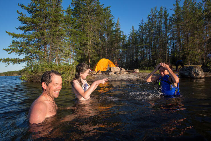 People enjoying swimming in the water next to their campsite.