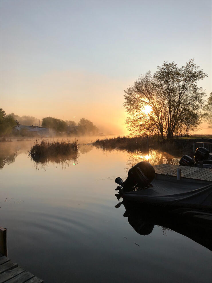 motorboat sits at dock in the misty dawn lakeside light