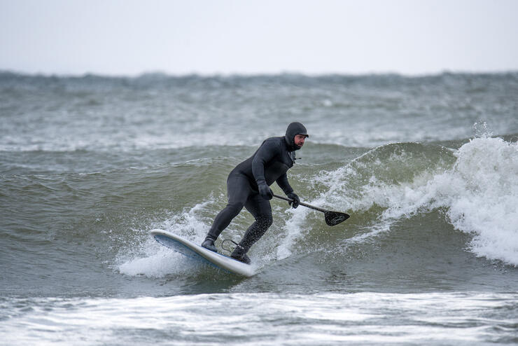 Man surfing on a SUP wearing a wetsuit