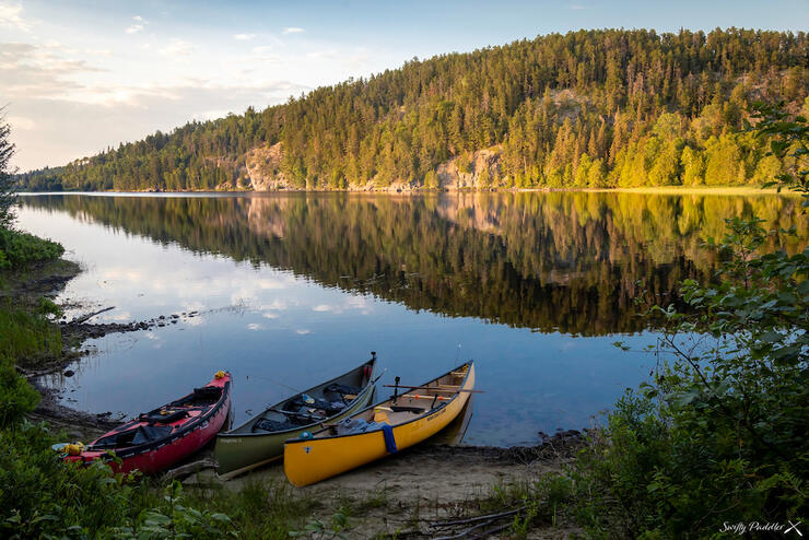 Three canoes on shore of a river.