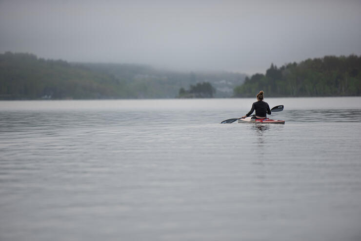 Person in a kayak on a lake on a gray morning.