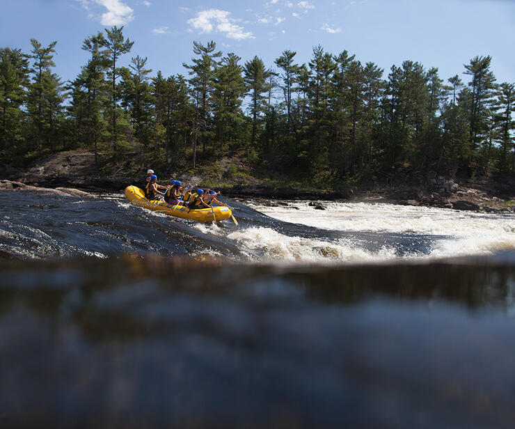 Group in a yellow raft gong down the rapids 