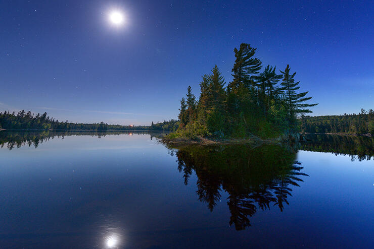 Moon rising over a calm lake.