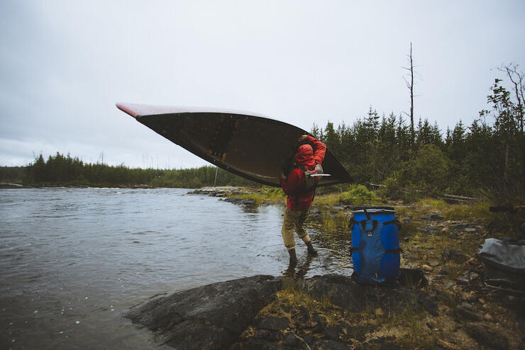Person lifting canoe over their head at the start of a portage.