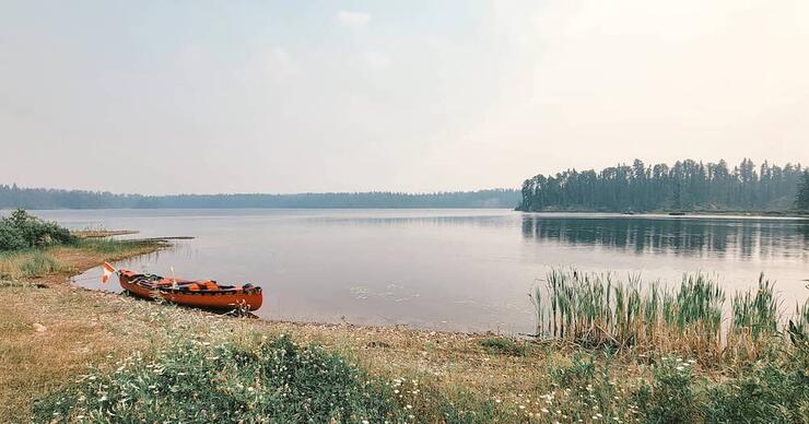 Red canoe pulled up on shore.