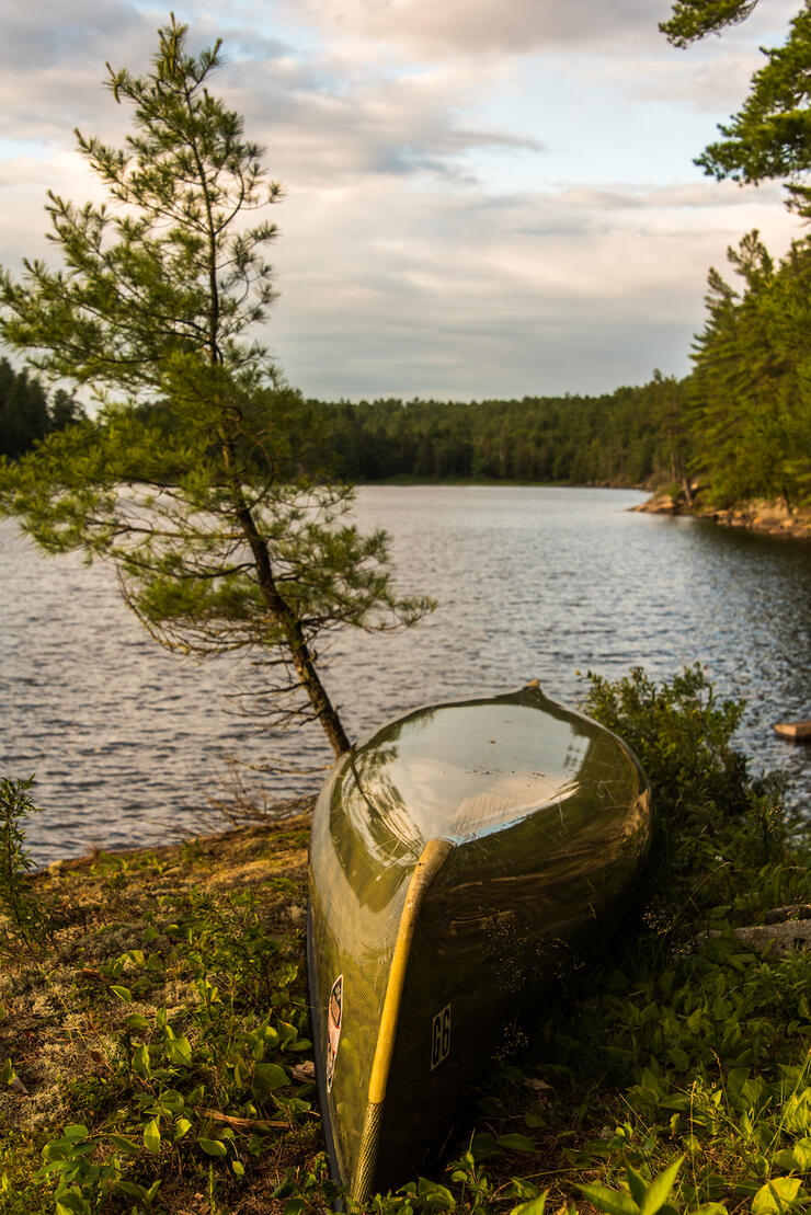 Canoe upside down on shore at sunset.