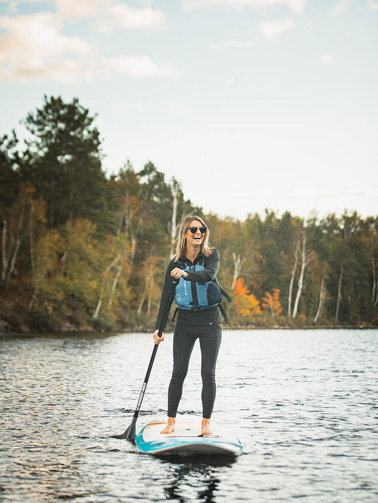 woman laughs while standup paddleboarding at Kivi Park in Sudbury