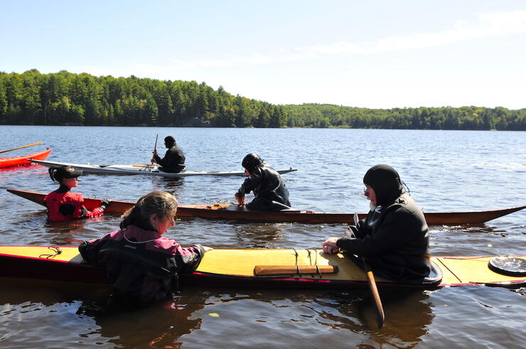 Kayaks in water with instructors standing in water beside kayaks