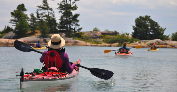 Woman paddling in kayak among sheltered smooth rock islands 