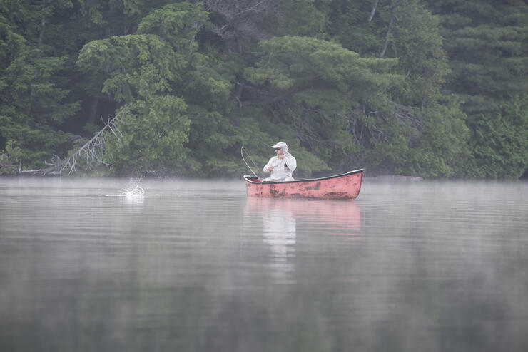 man fishing from canoe