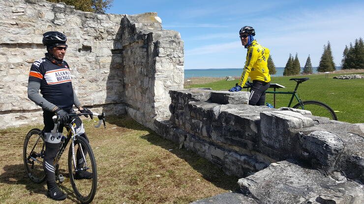 two cyclists stop at an old stone ruin on St. Joseph Island