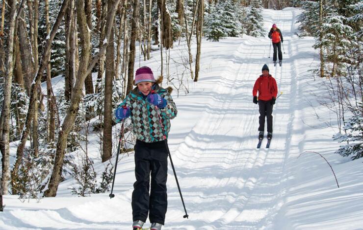 a family cross country skiis down a groomed trail