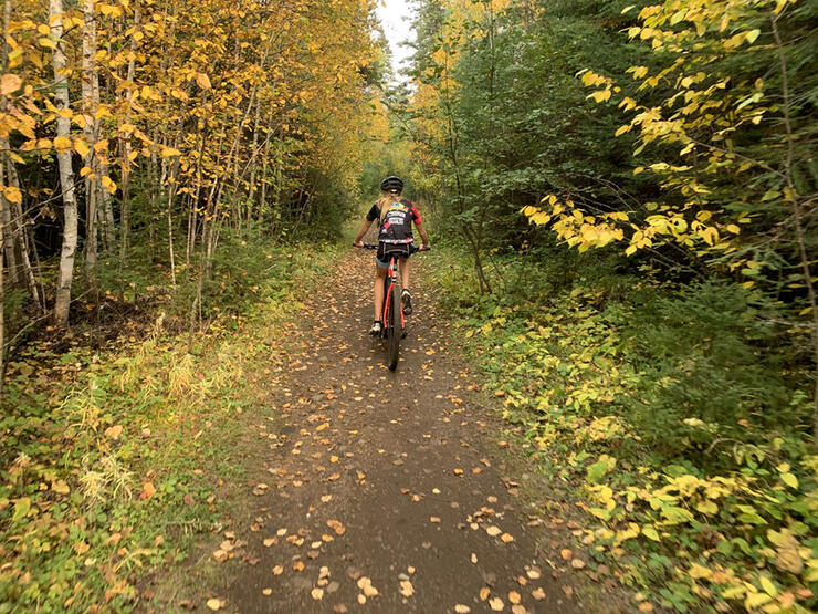 girl rides mountain bike down trail in fall