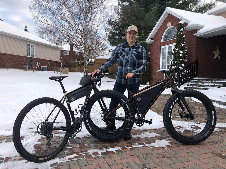 Tim Clayton poses with two fat bikes in front of a home in North Bay in wintertime