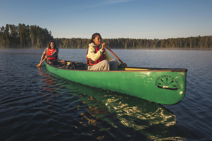Man and woman paddling a green canoe