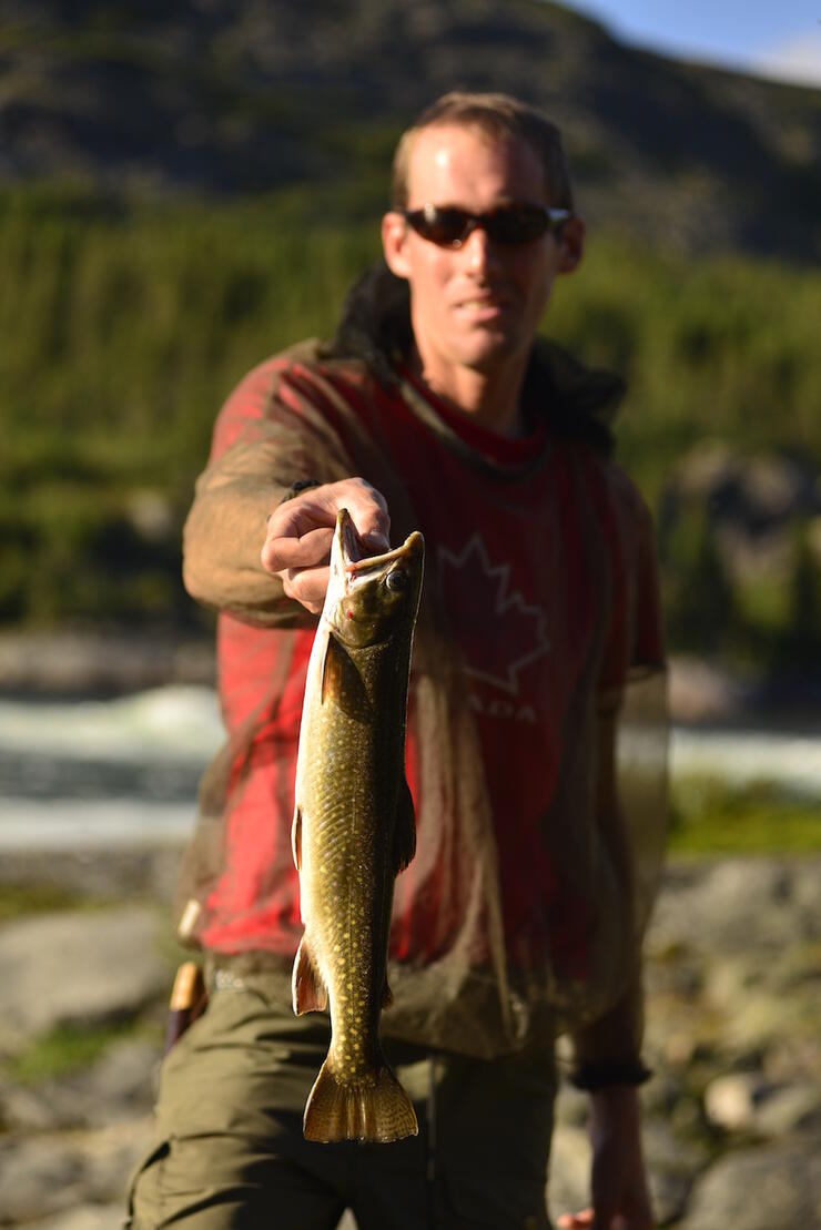 Man holding a lake trout by the mouth 
