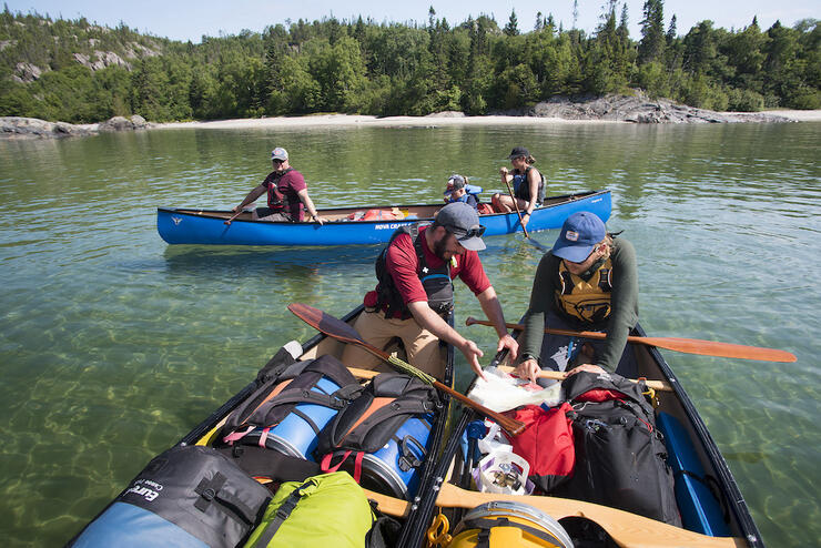 People looking at map in a fully loaded canoe.