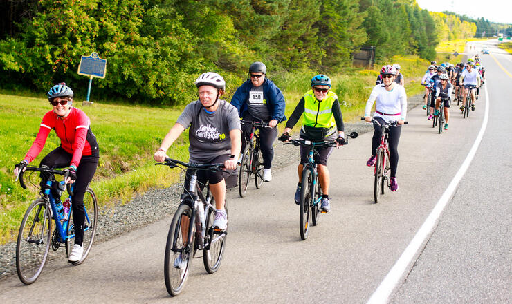 Large group of cyclists riding on paved shoulder of road