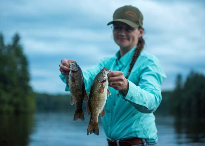 woman angler holding 2 smallmouth bass