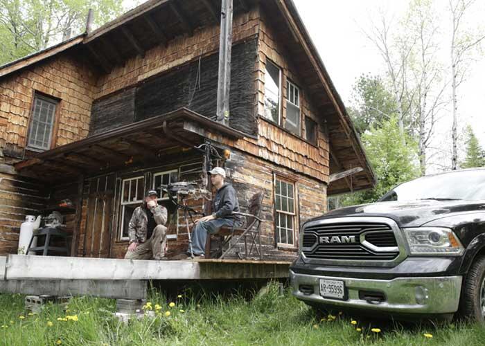 2 hunters sitting on cabin porch