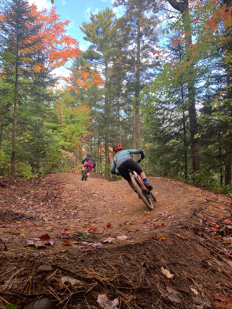 two cyclists ride through a forest trail at Hiawatha Highlands