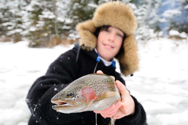 young ice angler holding trout