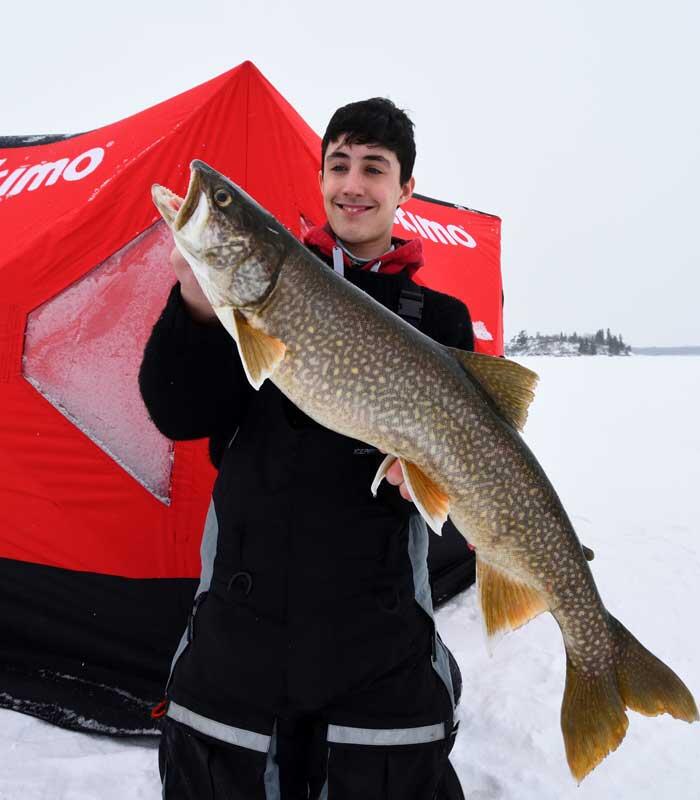 young ice angler holding lake trout