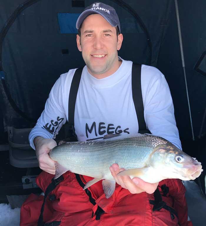 ice angler holding whitefish