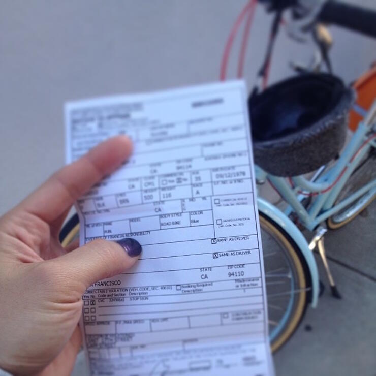 Woman holding a ticket in front of a bike