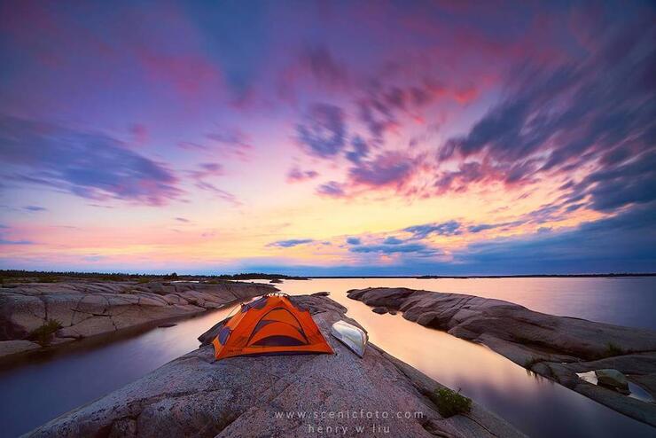 Tent set up near water with sunset
