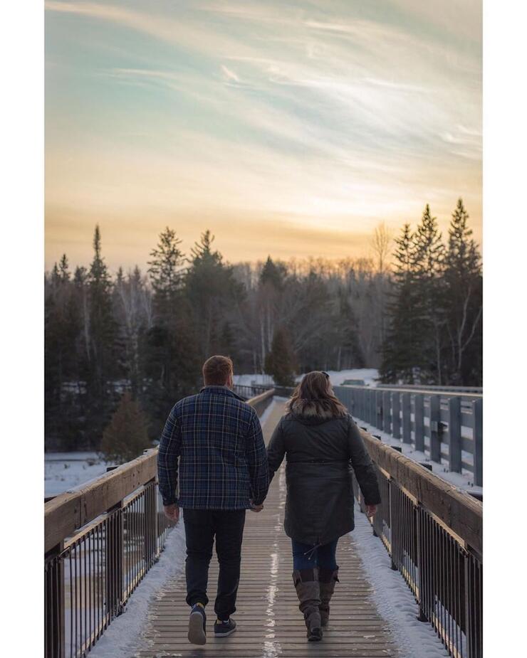 Couple holding hands while walking on boardwalk