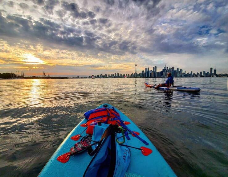 Two people paddleboarding with Toronto skyline in background