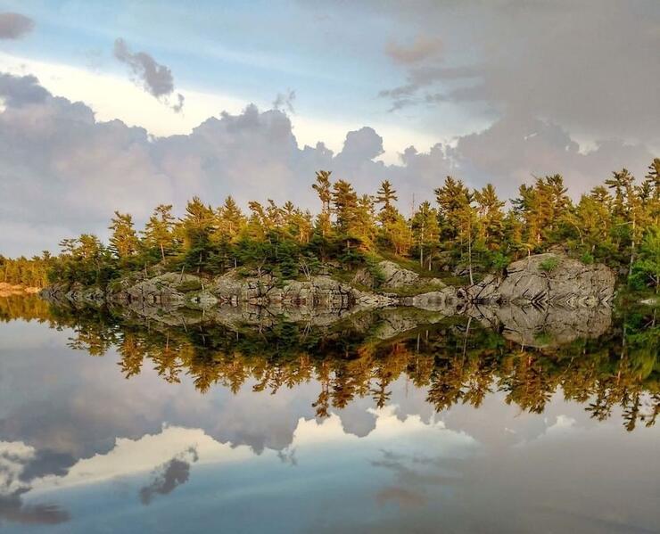 Trees and rocks reflected in lakewater.