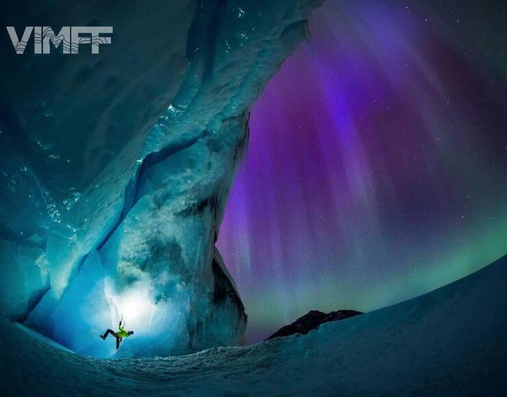 Someone ice-climbing with northern lights in background
