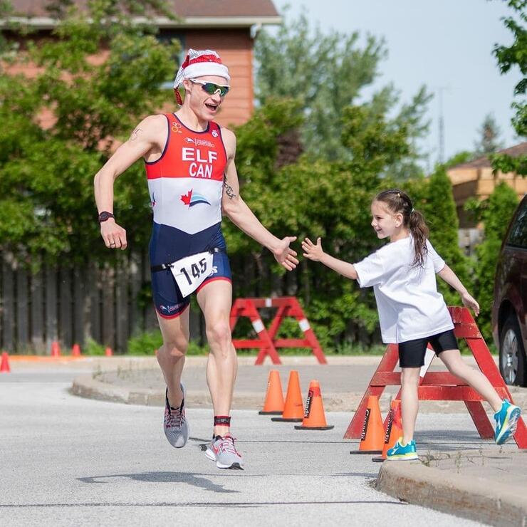 Male athlete in santa hat running on pavement in a race. 