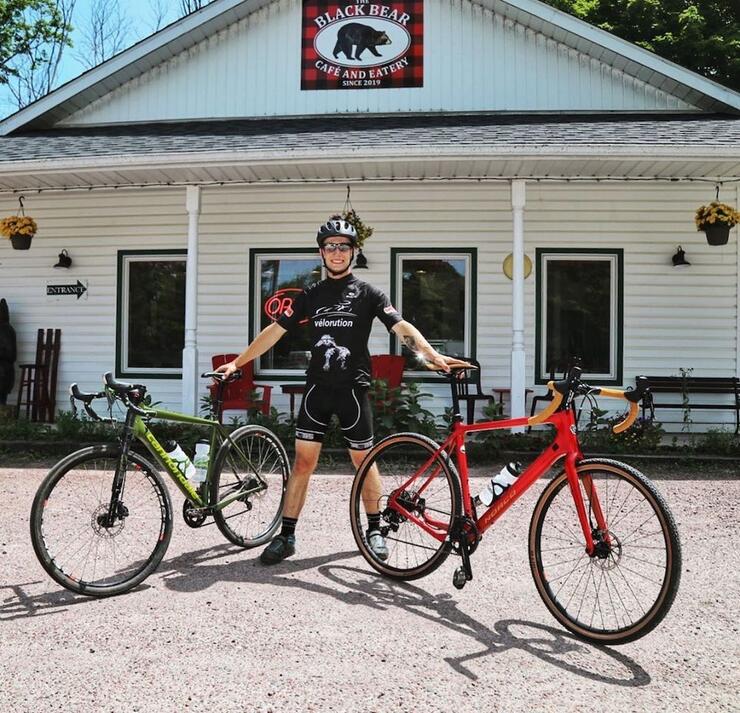 Person holding two bikes standing outside Black Bear Cafe and Eatery