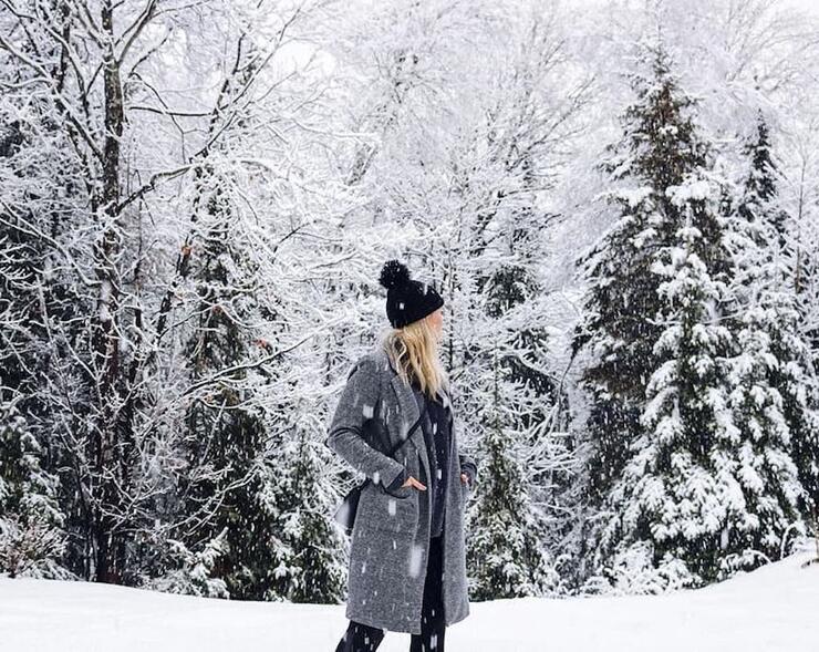 Woman walking among snow-covered trees.