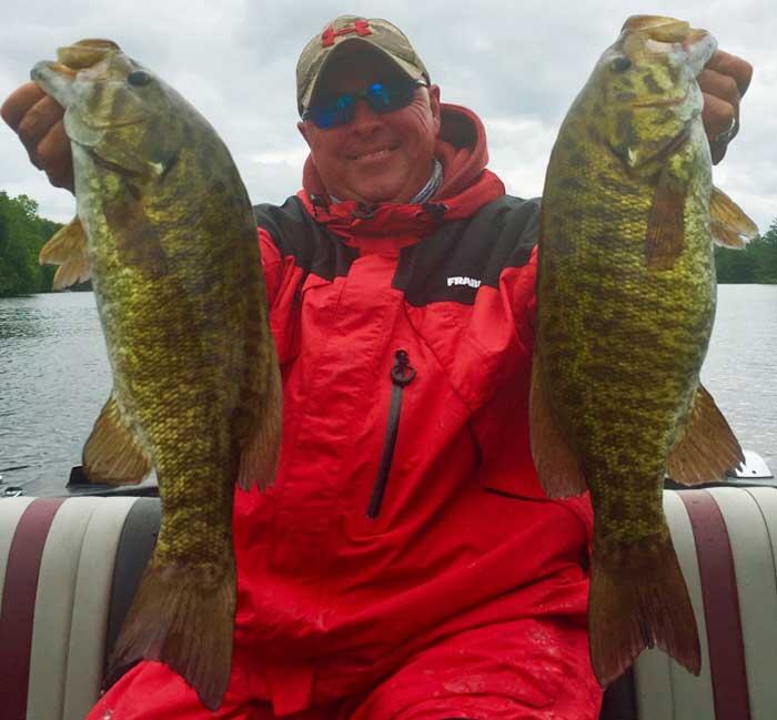 angler holding 2 smallmouth bass