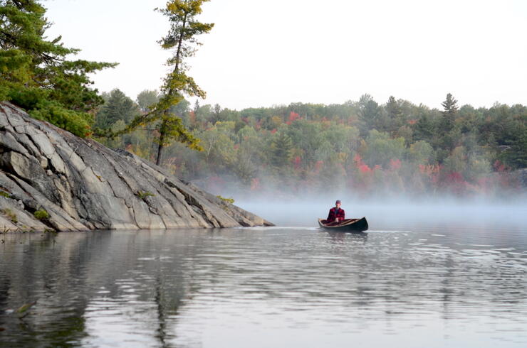 Canoeist paddling on misty lake