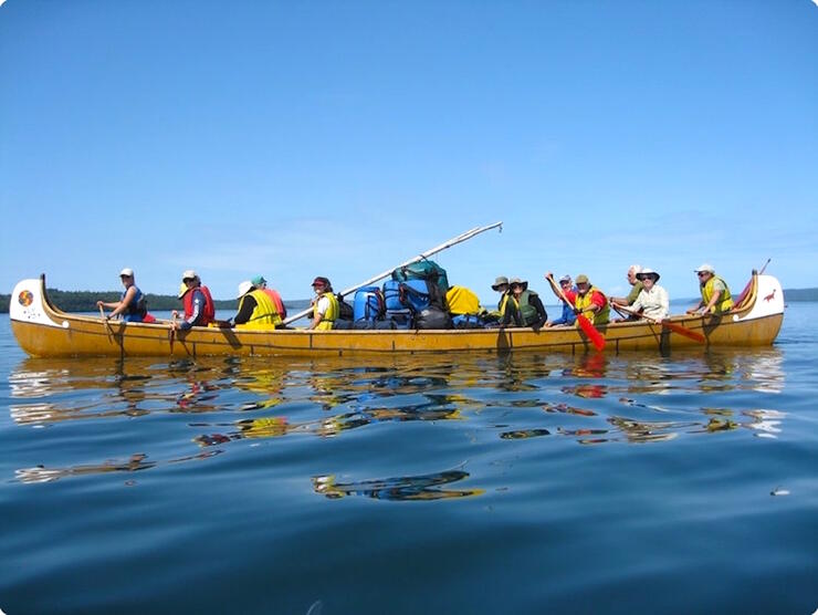 A group of people paddling a voyageur canoe. 