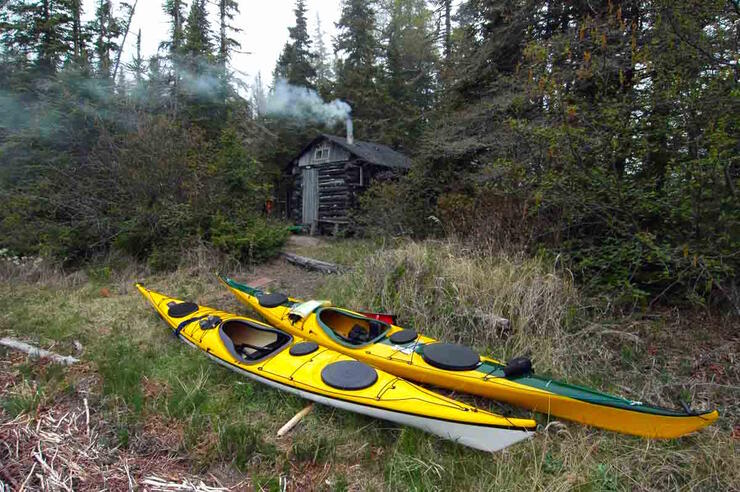 Two yellow kayaks in front of a wood fired sauna 