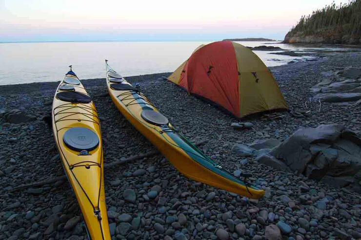Two kayaks and a tent on stone beach 